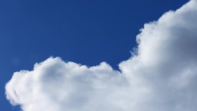 Zoom cinematic video of white cloud formations on a windy day in deep blue sky