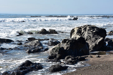 Asphalt Rock Formations with Waves Rolling Ashore