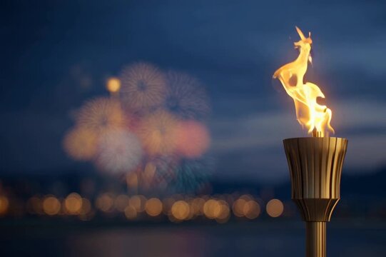 A lit torch stands prominently against a dark sky, with colorful fireworks bursting in the background. The scene captures the excitement of winter sports competitions in Italy.