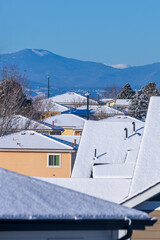 Snow-covered roofs in a Colorado neighborhood with the mountain range in the distance