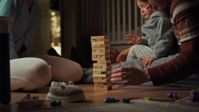 Mom, dad, and daughter snuggle up on the living room floor for a fun family evening, engrossed in a Jenga game together, fostering warmth and togetherness in their home