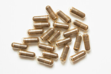 Capsules with brown powder on a white background, related to medications, supplements, treatment