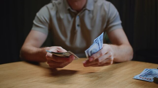 Close up: man trader or businessman counts salary usd banknotes at home with his hands. Male entrepreneur holds stack of dollar bills in palms, keeps money records for budget. Counting american paper