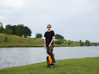 A young man on an electric unicycle poses in nature. Modern eco-friendly transport for driving