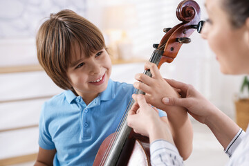 Little boy learning how to play violoncello with music teacher indoors © New Africa