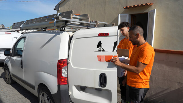 Professional electrical workers loading equipment and parts in service vehicle for delivery