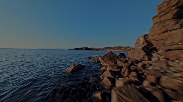A drone flies low and fast over coastal rocks on the shore of the sea. High quality 4k footage