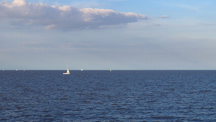 Lonely White Boat on Blue Sea Under Light Blue Sky with White Clouds