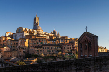 Naklejka premium Siena, Italy - March 27, 2019. Scenic view of old town of Siena in a sunset light