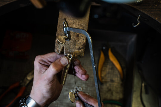 Jewelry craftsman cutting wire coiled on mandrel into links.