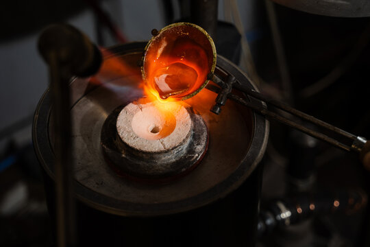 Jeweler pouring molten silver into a preheated mold for jewelry casting.