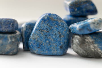 Close view of polished lapis lazuli stones stacked together, blue mineral blocks with calcite areas...