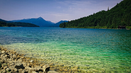 Summer peaceful atmosphere at lake with clouds and a forest at the background