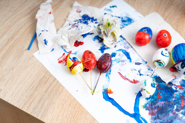 Colorful eggs and messy art supplies on a wooden table during an afternoon craft session at home