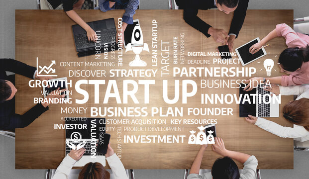 A diverse group of individuals engages in a collaborative startup brainstorming session, discussing innovative strategies and business plans over a wooden table filled with ideas. Tessel