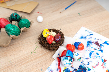 Kids paint colorful eggs for spring craft activity at home in the afternoon with art supplies spread on the table
