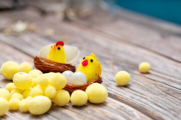 Bright yellow decorative chicks in wooden nests with colorful eggs on a wooden surface during a spring celebration