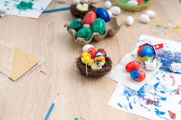 Children paint colorful Easter eggs on a table in a creative art activity during the spring holiday