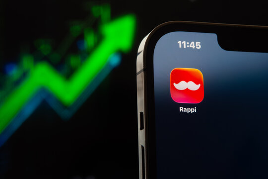 Rappi app icon on smartphone with bullish stock market chart in the background, e-commerce boom concept. Sonora, Mexico - January 27, 2026