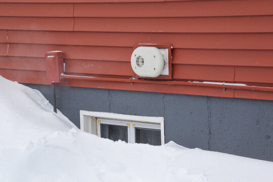 Furnace or boiler exhaust vent on outside of house with steam coming out. Keeping house exhaust clear of snow to prevent carbon monoxide poisoning. Clear away snow from home vents for safety