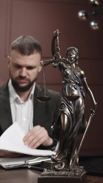 Attorney working on laptop in professional law office with Lady Justice statue. Legal research, justice system, law practice and modern attorney workplace.