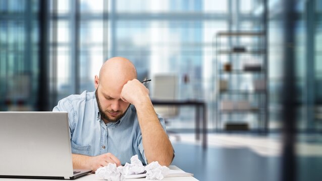 Sad tired male worker in office with deadline