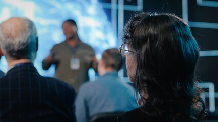 Senior female in the audience listening to AI sales pitch featuring neural networks, AI brain...