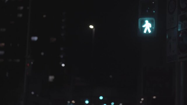 夜の横断歩道、青から赤に変わる歩行者用信号機と背後を通過する電車