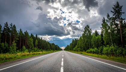 Obraz premium Asphalt road stretching into the distance under a dramatic cloudy sky.