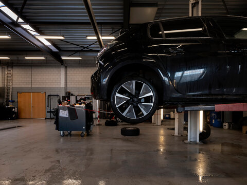 Car workshop workbench area with various tools and supplies, tiled wall background, authentic working environment
