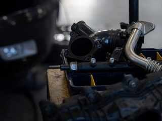 Obraz premium Car engine thermostat housing and coolant system parts on workshop bench, automotive repair components close-up