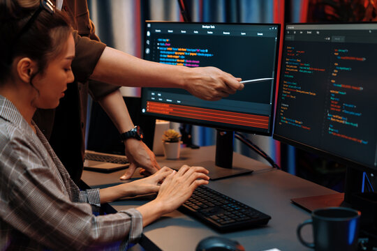 IT developers discussing with point to intelligent website development coder system running data online two screens information technology at neon light room at modern office. Infobahn.