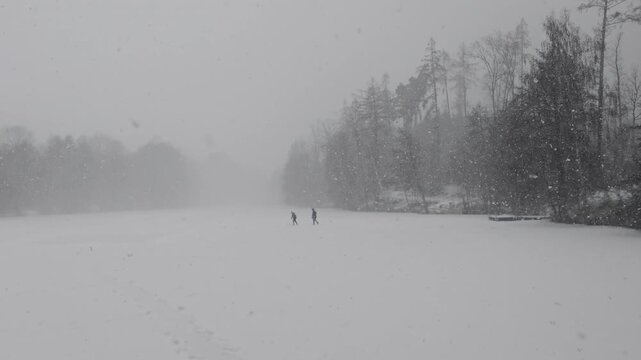 Winter holidays scene with father and son playing together on an icy surface of a frozen lake surrounded by forest, capturing family bonding, childhood joy, and winter nature