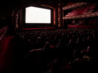 Full theatre audience watching projection screen from behind, historic Art Deco cinema interior with balconies © Victor