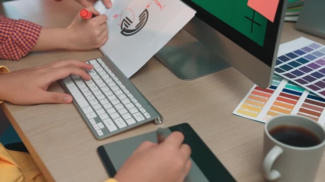 A modern workspace featuring a computer, color samples, and a digital tablet, highlighting the creative process and collaboration in a professional office setting. SACTR