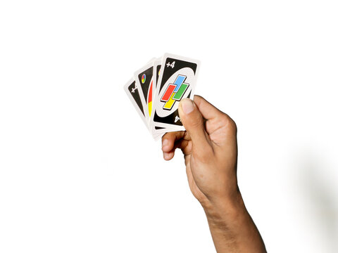 Semarang, Indonesia - January 1, 2026: Man's hand holding Uno game cards isolated on white background