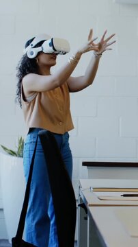 Vertical video: VR activating woman in sleeveless top pinching, tapping to control at desk with bag