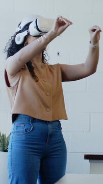 Vertical video: Pinching woman in tan top navigating UI with VR headset and smartwatch in office
