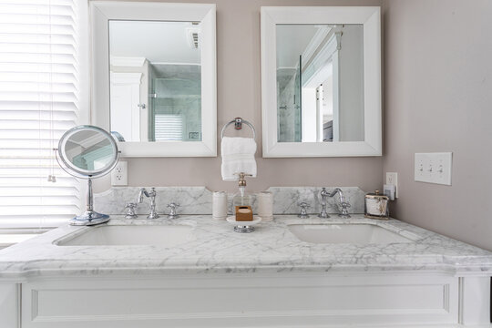 Elegant double bathroom vanity with marble countertop, twin sinks and mirrors in a bright modern interior