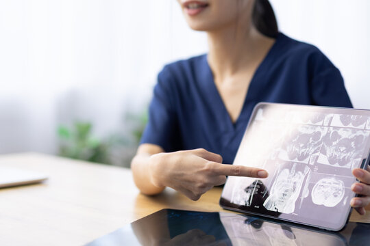 X-ray Image on Digital Tablet Explained by Female Healthcare Worker