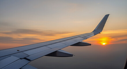 Obraz premium Airplane wing soaring through the sky during a breathtaking sunset