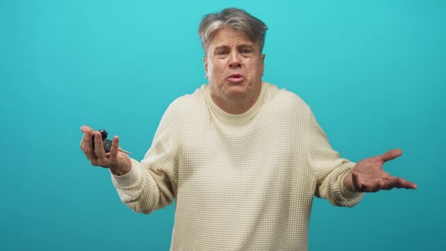 Middle-aged grey-haired man holding car keys and shrugging with open palms in studio; frustration over remote failure.