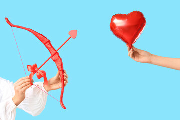 Female hands with cupid's bow and heart shaped balloon on color background. Valentine's Day...
