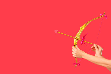Naklejka premium Female hands with cupid's bow on red background. Valentine's Day celebration