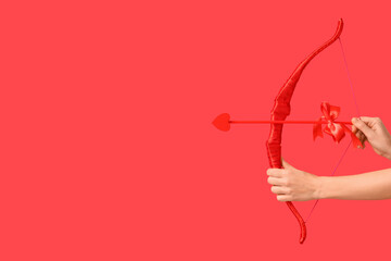 Naklejka premium Female hands with cupid's bow on red background. Valentine's Day celebration