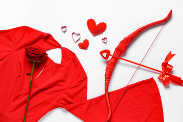 Naklejka premium Composition with red dress, cupid's bow and rose flower on light background. Valentine's Day celebration