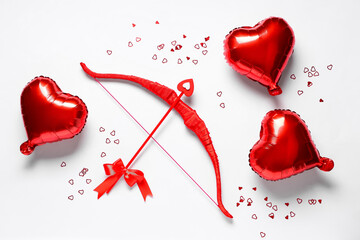 Naklejka premium Composition with red cupid's bow and heart shaped balloons on light background. Valentine's Day celebration