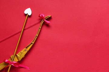 Naklejka premium Golden cupid's bow with arrow on red background. Valentine's Day celebration
