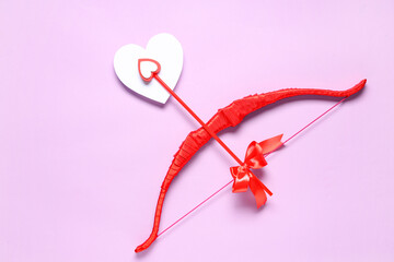 Naklejka premium Red cupid's bow with paper heart on lilac background. Valentine's Day celebration
