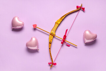 Naklejka premium Golden cupid's arrow and heart shaped balloons on lilac background. Valentine's Day celebration